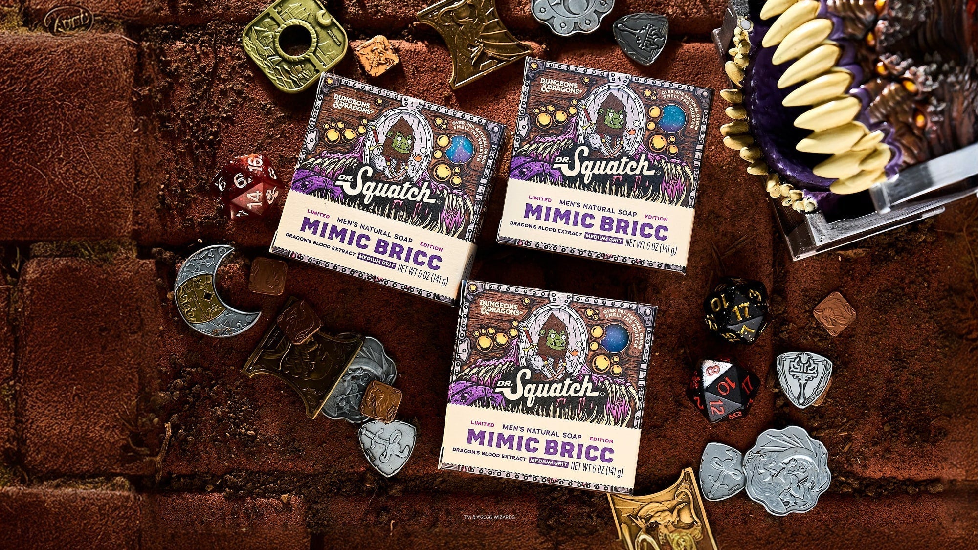 Three boxes of Dr. Squatch Mimic Bricc natural soap surrounded by Dungeons & Dragons dice and metal tokens on a textured brown surface.
