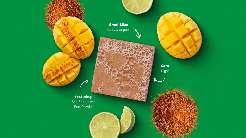 Mango exfoliating bar surrounded by fresh mangoes, lime slices, and cinnamon-chili powder on green background.